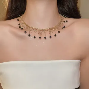 Vue détaillée d'un collier ras du cou en dentelle dorée avec glands en cristal noir
