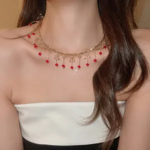 Vue détaillée d'un collier ras du cou en dentelle dorée avec des perles de cristal rouges.