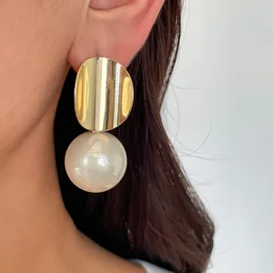 Nahaufnahme von Vintage Gold-Geometrie-Ohrringen mit einer großen Perle am Ohr.
