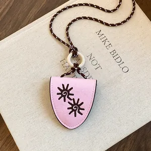 Vue détaillée du collier pince à lunettes en cuir rose avec motifs de soleil brodés.