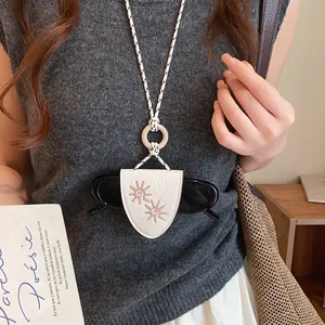 Gros plan d'un collier porte-lunettes en cuir vintage avec broderie soleil porté par mannequin.