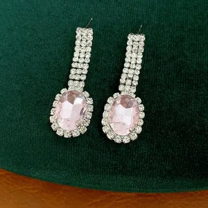 Detailansicht eleganter Ohrringe mit rosa Strasssteinen auf luxuriösem grünem Samthintergrund