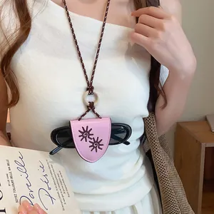 Gros plan d'un collier porte-lunettes en cuir rose avec motif de tournesol sur un mannequin