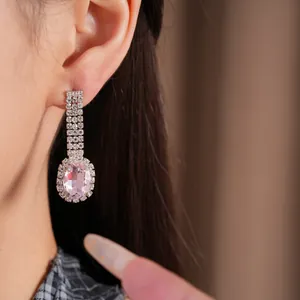 Elegante rosa ovale Ohrringe mit glänzenden Kristallakzenten im Detail am Model