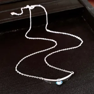 Vista dettagliata di una collana d'argento con pendente rotondo in zirconia blu chiaro.