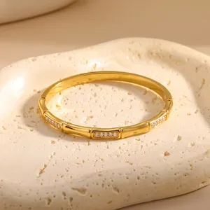 Detail van 18k vergulde armband met bamboe-ontwerp en zirkonia-inleg op een stenen schaal