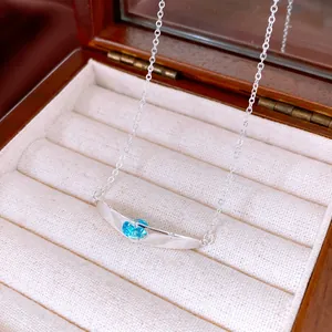 Dettaglio di elegante collana in argento con zircone blu in una scatola di legno