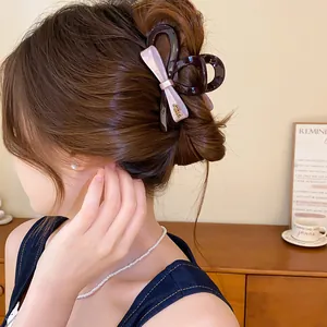 Detail van een acryl haarklem met roze strik gestyled op een klassieke bruine knot