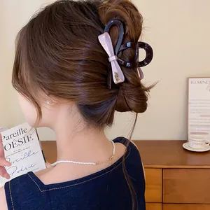 Detailopname van een elegante roze haarclip met strik gestyled op een bruine knot
