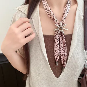 Detail view of a vintage leopard print fabric necklace with a silver flower pendant.