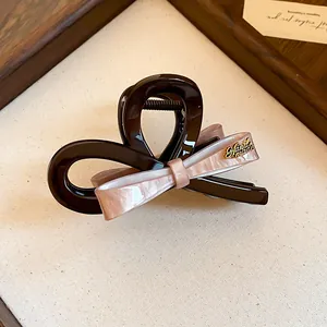 Detail van roze acryl haarklem met strik en gouden handgemaakt metalen embleem