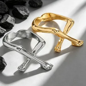 Nahaufnahme abstrakter offener Ringe mit gekreuzten Gliedmaßen in Gold und Silber