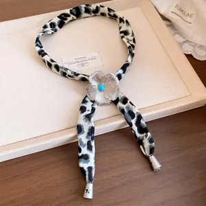 Close-up of leopard print fabric necklace with silver resin flower charm.