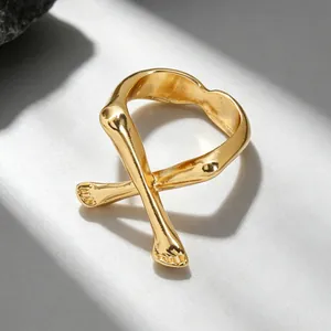 Detailansicht eines abstrakten Rings mit gekreuzten Gliedmaßen in antikem Gold-Finish