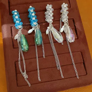 Nahaufnahme von luxuriösen Glastropfen-Ohrringen mit Kristallperlen auf einem Samttablett.