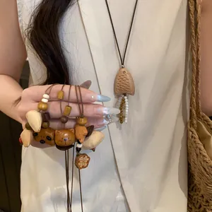 Detailed close-up of handmade wooden animal and shell pendants on brown leather cords