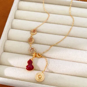Close-up detail of 18k gold plated necklace featuring a red gourd and Fu character charms
