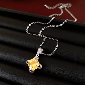 Close-up detail of an elegant rhombus yellow zircon pendant necklace on black display tray