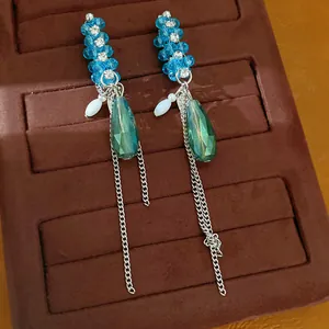 Nahaufnahme von blauen Glasperlen-Ohrringen mit silbernen Kettenquasten auf braunem Samt