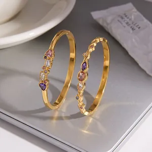 Detail of gold stainless steel bangles with colorful heart and geometric stones