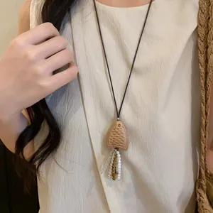 Close-up detail of retro wooden fish pendant necklace with leather cord and colorful beads