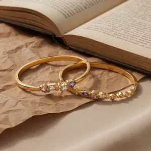 Close-up of gold-plated stainless steel bangles with colorful heart and geometric crystals.