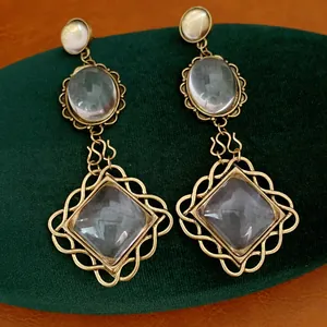 Detailed view of vintage gold-tone earrings with oval and diamond-shaped glass elements.
