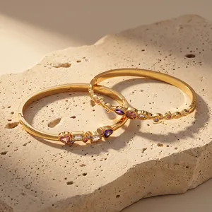 Detailed view of two gold stainless steel bracelets with colorful heart and geometric stones