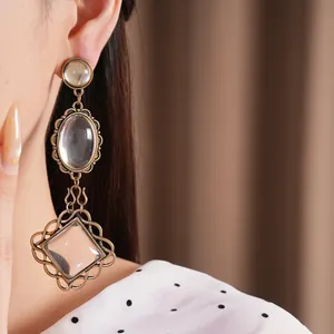 Close-up of vintage bronze earrings with oval and diamond crystal drops on model