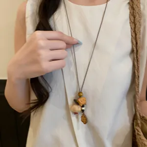 Detail view of retro ethnic style long necklace with wooden fish and shell pendants.