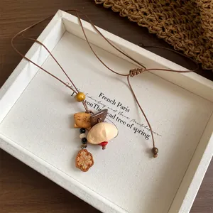 Detail showing handmade ethnic pendant necklace with wooden fish and shell charms