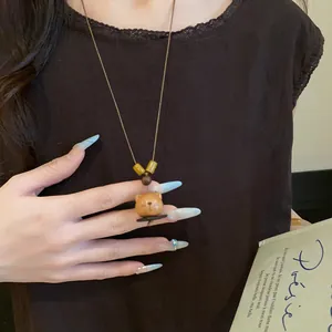 Close-up detail of retro wooden bear pendant necklace with leather cord worn by model