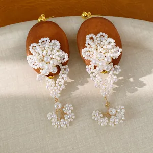 Detailed close-up of vintage oval wood earrings with handcrafted pearl flower tassels