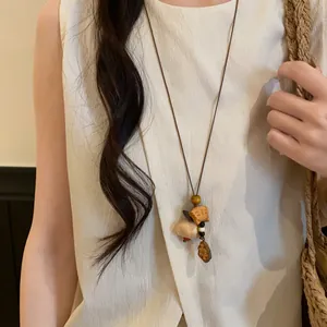 Close-up of retro ethnic necklace with wooden animal and shell pendants on cord.
