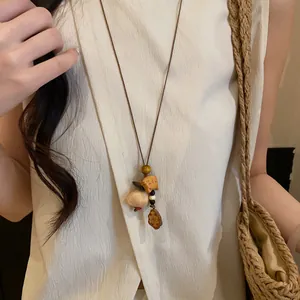 Close-up of a vintage ethnic style necklace with wooden fish and shell pendants on a model.