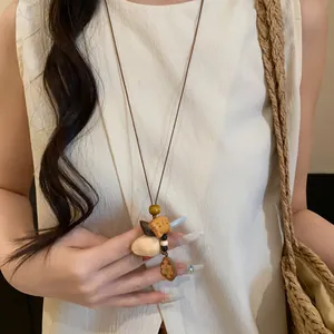 Detail of ethnic style necklace with wooden animal and shell pendants on cord
