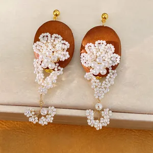 Detailed view of elegant vintage oval wood earrings with beaded pearl flower tassels.
