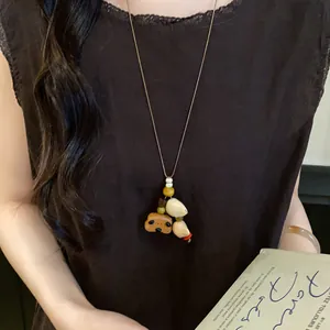 Detail view of a vintage folk style necklace featuring a wood bear charm and shells