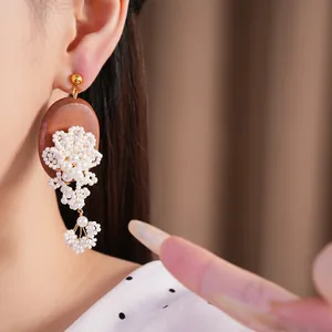 Close-up of vintage wood and pearl beaded flower tassel earring on Asian model
