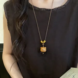 Close-up of a vintage handmade wooden bear pendant necklace on a brown leather cord