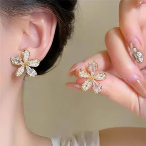 Vue détaillée de boucles d'oreilles fleurs dorées 18K avec perles et zircons brillants