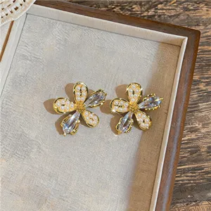 Vue détaillée d'élégantes boucles d'oreilles fleurs dorées avec perles et cristaux brillants