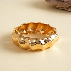 Detail van een goudkleurige golvende geplooide metalen armband met een hoogglans afwerking