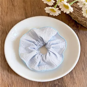 Gros plan d'un chouchou en tissu bleu clair texturé avec des bords délicats en dentelle