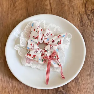 Détail d'un chouchou à imprimé fraise avec bordures en dentelle et un nœud rouge