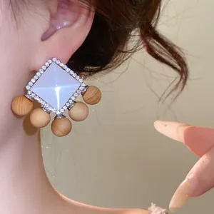 Macro view of French vintage stud earrings with white resin and light wood ball drops.