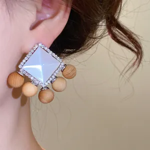 Detailed view of vintage resin earrings with wooden beads and rhinestones worn on ear