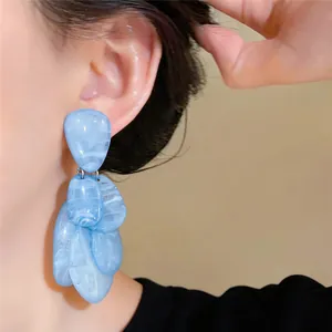 Detailopname van blauw gemarmerde hars oorbellen in druppelvorm gedragen door een model