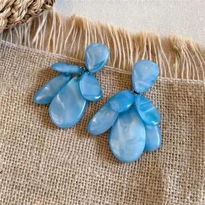 Detailopname van blauwe marmeren hars oorbellen met swirl patronen op linnen textuur