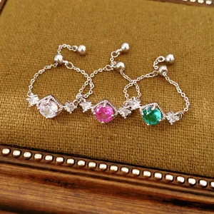 Detail van drie verstelbare zilveren kettingringen met witte, roze en groene zirkoonstenen.